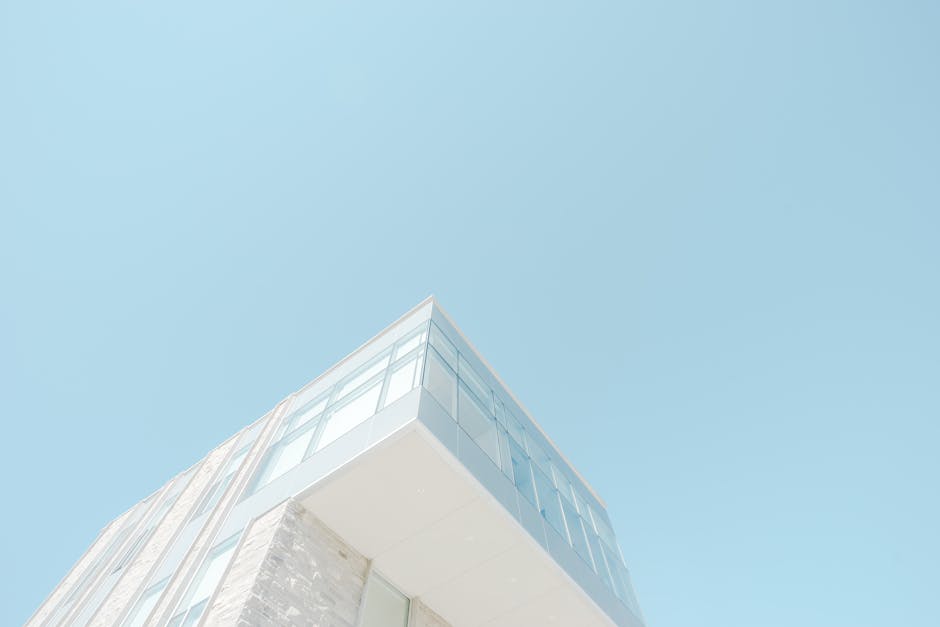 A low-angle shot of a modern building with a glass facade against a bright blue sky in London, Canada